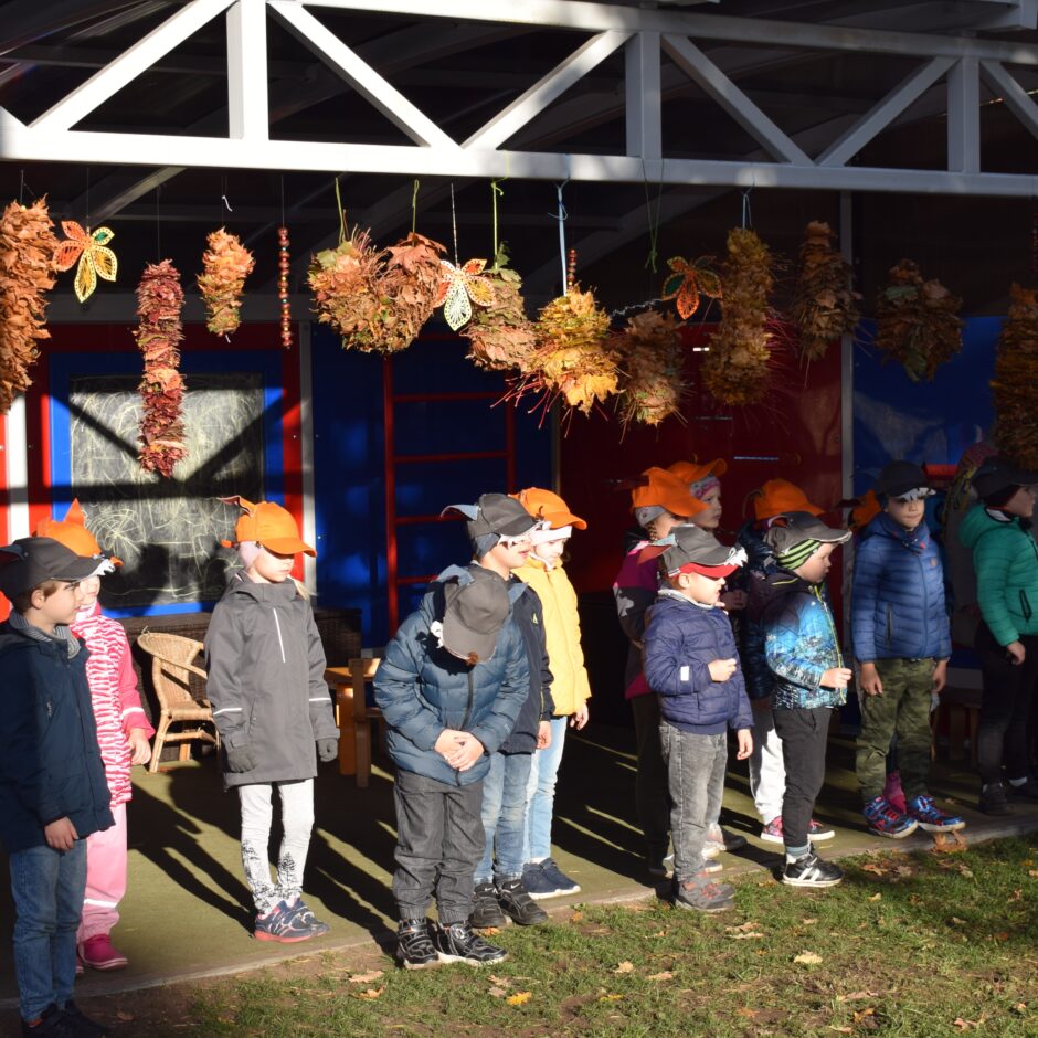 Bērni tērpušies kostīmos un dejo bērnudārza pagalmā.