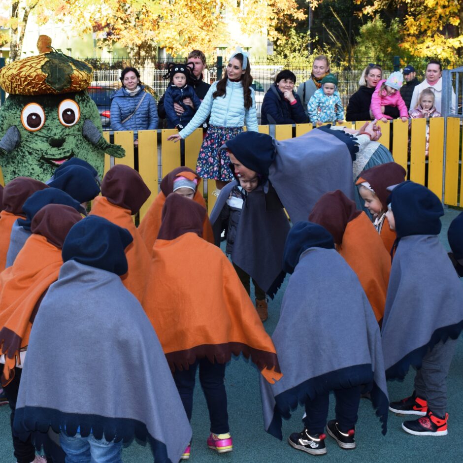 Bērni tērpušies kostīmos un dejo bērnudārza pagalmā.