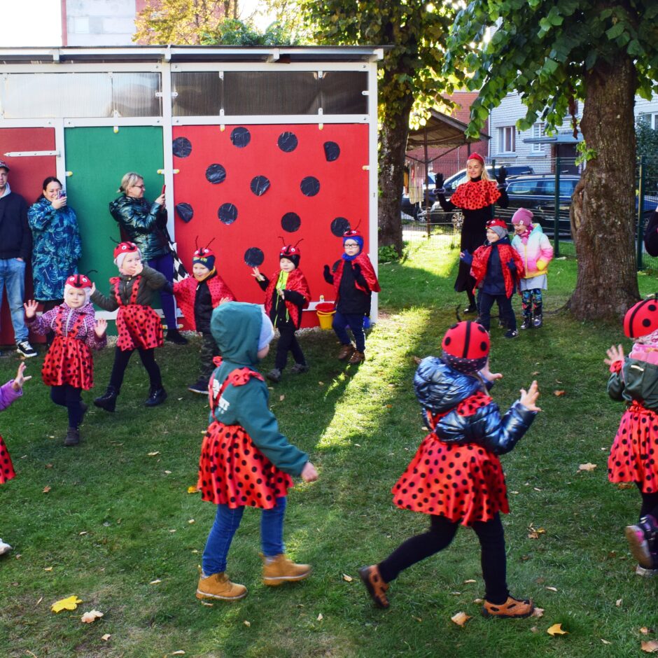 Bērni tērpušies kostīmos un dejo bērnudārza pagalmā.