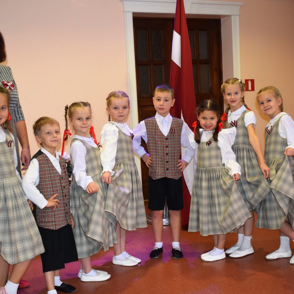 Bērni svin valsts svētkus aktu zālē.