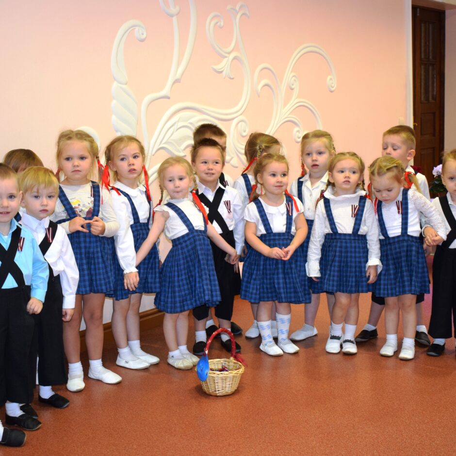 Bērni svin valsts svētkus aktu zālē.