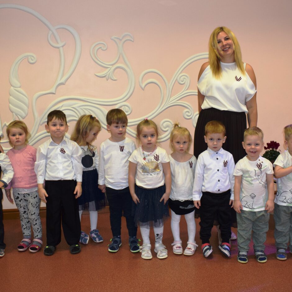 Bērni svin valsts svētkus aktu zālē.