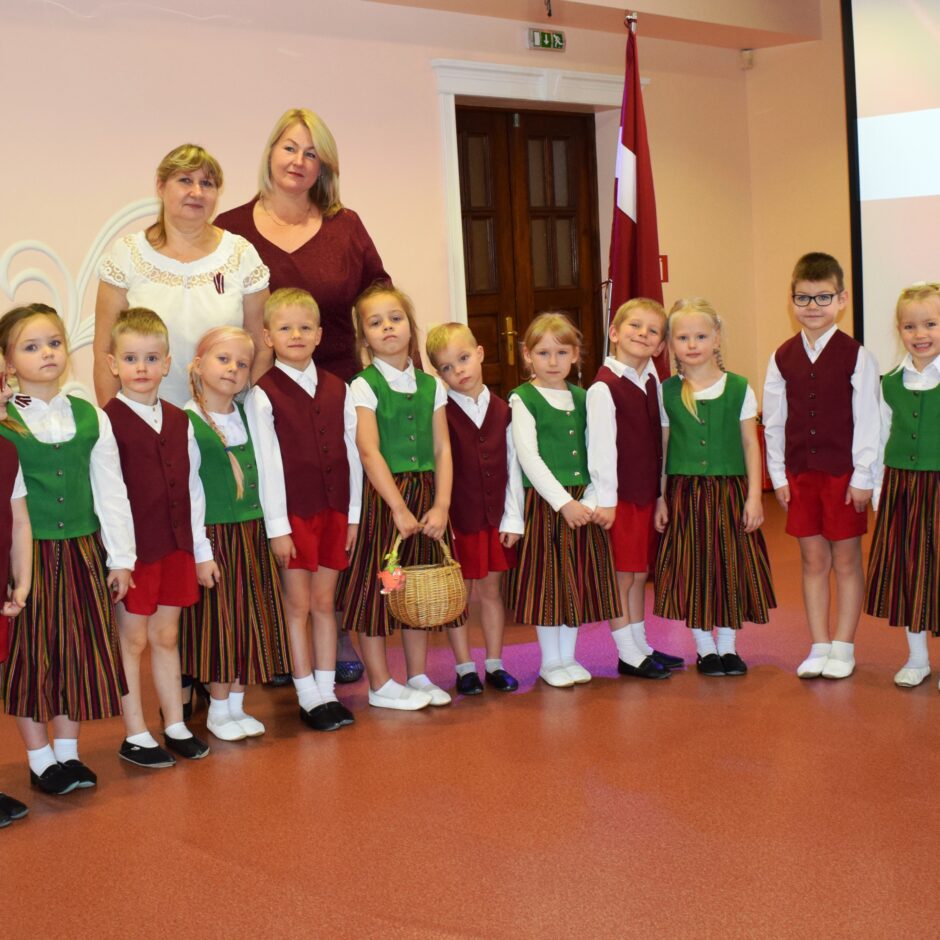 Bērni svin valsts svētkus aktu zālē.