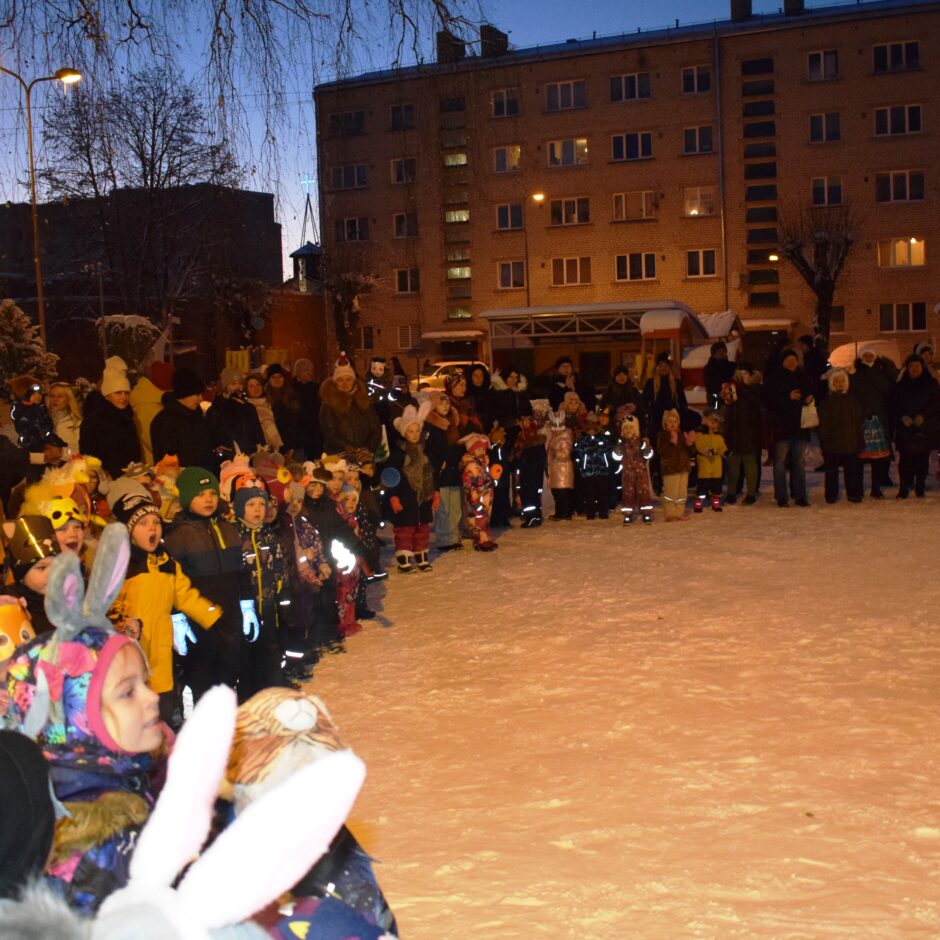 Bērni ar vecākiem stāv pusaplī.
